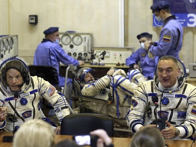 FILE - In this Tuesday, March 25, 2014 file photo, U.S. astronaut Steven Swanson, left, and Russian cosmonaut Alexander Skvortsov, crew members of the mission to the International Space Station, speak with relatives during pre-launch preparations at the Russian-leased Baikonur cosmodrome in Kazakhstan. Cosmonaut Oleg Artemyev is at center background. In an announcement Wednesday, April 2, 2014, NASA says it is suspending its work with Russia except for the International Space Station. The move comes a week after the space agency said U.S.-Russian space relations were fine despite Russia's annexation of the Crimean Peninsula from Ukraine. NASA employees are barred from traveling to Russia until further notice. Workers also can't email or hold teleconferences with their Russian counterparts. (AP Photo/Maxim Shipenkov, Pool, File)