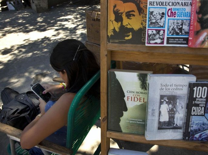 A book street vendor passes the time on her smart phone as she waits for customers in Havana, Cuba, Tuesday, April 1, 2014. The Obama administration secretly financed a social network in Cuba to stir political unrest and undermine the country’s communist government according to an Associated Press investigation. The project, dubbed "ZunZuneo," slang for a Cuban hummingbird’s tweet, lasted more than two years and drew tens of thousands of subscribers and sought to evade Cuba’s stranglehold on the Internet with a primitive social media platform. First, the network would build a Cuban audience, mostly young people; then, the plan was to push them toward dissent. (AP Photo/Ramon Espinosa)