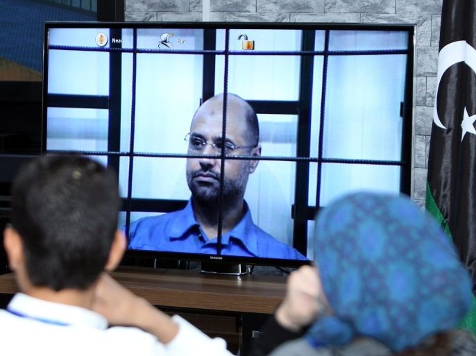 Journalists watch Saif al-Islam, the son of former Libyan leader Muammar Gaddafi, on a screen broadcasting his trial taking place in Zintan to journalists at a courtroom in Tripoli, Libya, 27 April 2014. Two sons of former Libyan leader Gaddafi are facing charges for crimes allegedly committed in an attempt to abort the uprising that toppled their father. Saadi and Saif al-Islam Gaddafi are among 37 defendants facing charges that include incitement to kill and rape opponents, enlisting mercenaries and embezzlement of public funds and other abuses during the 2011 uprising that led to the ouster and killing of Gaddafi.