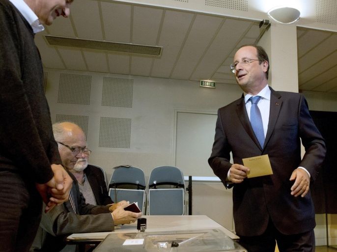 French President Francois Hollande (R) speaks with election officers as he prepares to cast his ballot for the European parliament elections on May 25, 2014 at a polling station in Tulle, centralwestern France. Twenty one European Union member states headed to the polls today on the fourth and final day of voting for the European Parliament which began in Britain and the Netherlands on May 22.AFP PHOTO POOL/ ALAIN JOCARD