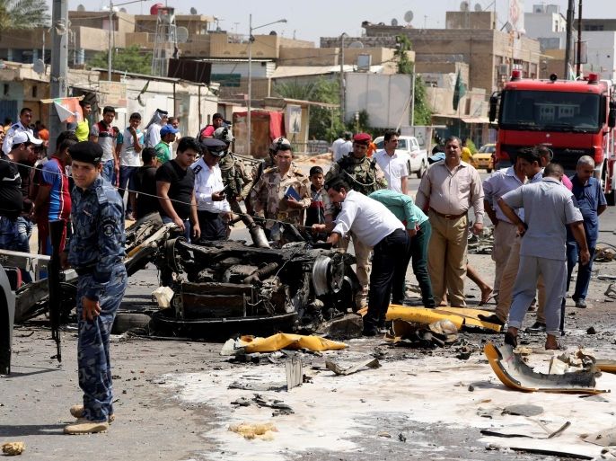 Security forces and civilians inspect the site of a car bomb explosion in the Shiite stronghold of Sadr City, in Baghdad, Iraq, Tuesday, May 13, 2014. A wave of car bombings in mainly Shiite areas of Baghdad killed dozens of people on Tuesday, officials said, the latest in a surge in violence that has been the most serious challenge to the government's efforts to achieve stability across Iraq. The attacks came as Iraqi Shiites were celebrating the birthday of Imam Ali, the cousin and son-in-law of the Prophet Muhammad and Shiite Islam's most sacred martyr. (AP Photo/Karim Kadim)