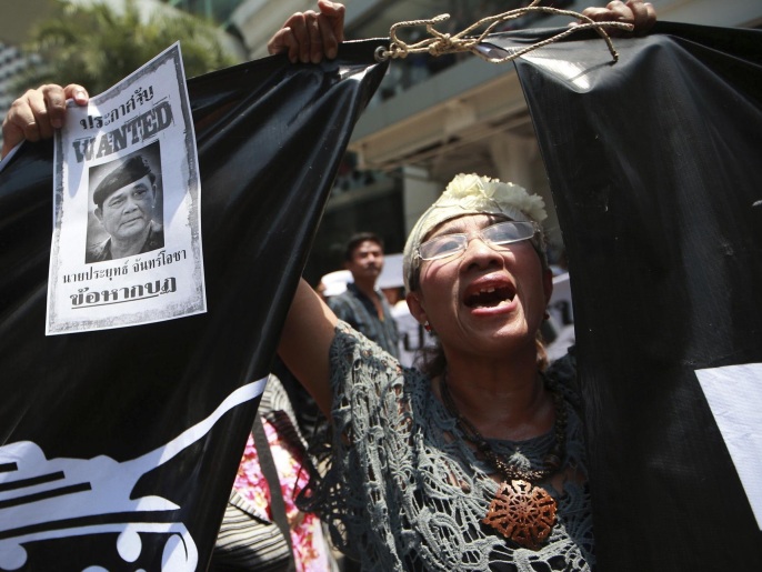 امرأة تحمل صورة قائد الانقلاب كتب تحتها  مطلوب القبض عليه (أسوشيتد برس)
