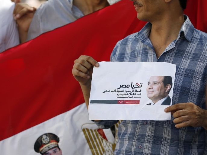 An Egyptian national residing in the United Arab Emirates holds his passport and an image of presidential canditade Ex-army chief Abdel Fattah al-Sisi, as he waits to cast his vote at the Egyptian embassy in Dubai, on May 15, 2014. Ex-army chief and leading presidential candidate Abdel Fattah al-Sisi is expected to win the May 26-27 election against his only rival, leftist Hamdeen Sabbahi, amid calls for a strong leader who can restore stability following the ousting of elected Islamist president Mohamed Morsi in July. AFP PHOTO/KARIM SAHIB