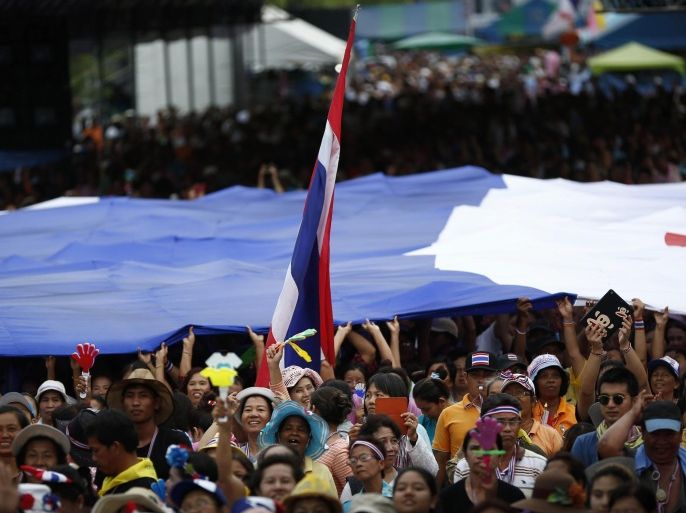 Anti-government protesters lift a giant Thai flag during a rally in Bangkok, Thailand, Wednesday, May 14, 2014. The leader of Thailand's anti-government movement pushed Tuesday for the appointment of an unelected prime minister in a news conference televised from the government's compound, which protesters have seized. Suthep Thaugsuban urged the Senate to name a new prime minister, arguing that the caretaker leader, Niwattumrong Boonsongpaisan, has no legitimacy. (AP Photo/Vincent Thian)