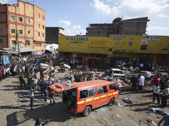 People gather at the scene of an explosion as police officers inspect a minibus that exploded in Gikomba market in Nairobi, Kenya, 16 May 2014. According to the local media, twin explosions caused by improvised explosive devices killed at least ten people and injured more than 80 people. Twin blasts come a few days after the United Kindom and the United States warned against travels to parts of the country due to possible terror attacks.