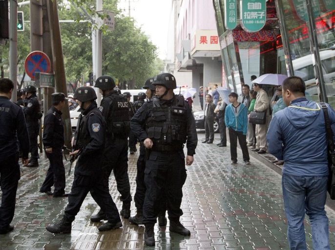 Armed policemen stand guard near the site of an explosion in Urumqi, northwest China's Xinjiang region, Thursday, May 22, 2014. Assailants in two SUVs plowed through shoppers while setting off explosives on a busy street market in China's volatile northwestern region of Xinjiang on Thursday, the local officials said, killing over two dozen people and injuring more than 90. The attack was the bloodiest in a series of violent incidents that Chinese authorities have blamed on radical separatists from the country's Muslim Uighur minority. (AP Photo/Andy Wong)