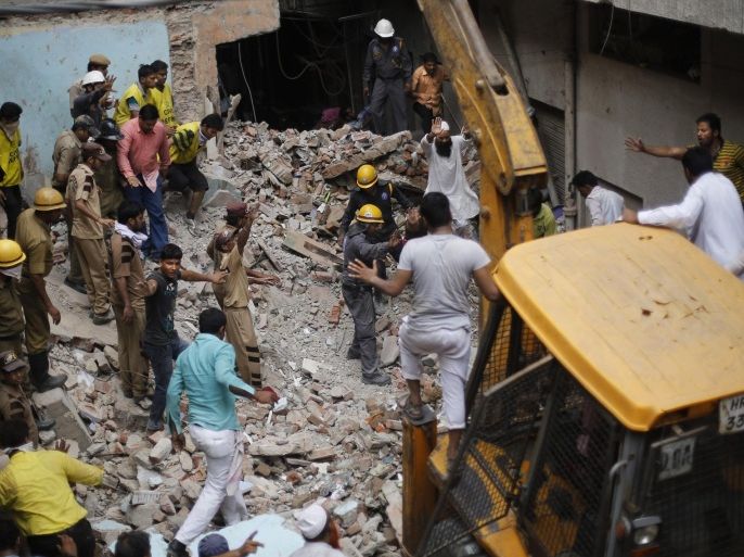 Indian rescuers gesture for an excavator to stop as they try to retrieve the body of a victim at the site of a building collapse in New Delhi, India, Saturday, June 28, 2014. A dilapidated building collapsed in the Indian capital on Saturday, killing at least seven people as rescuers searched for others believed to be trapped. (AP Photo/Altaf Qadri)