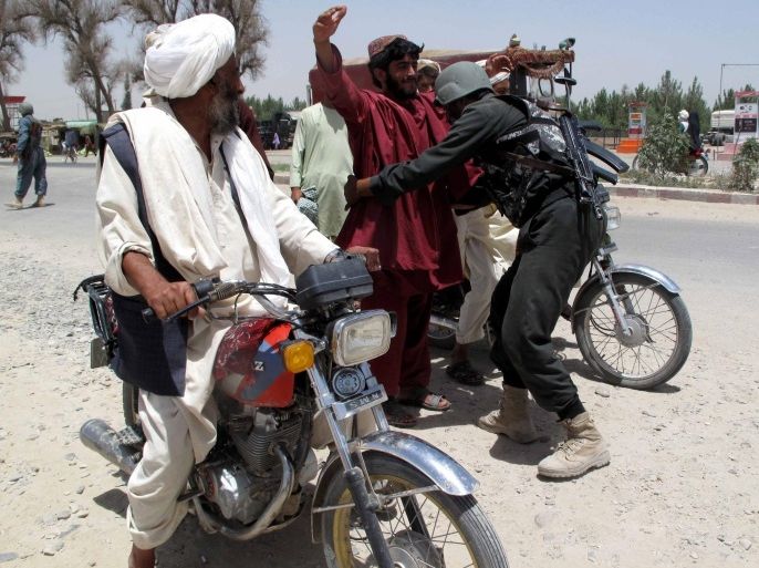 An Afghan security official frisks a man at a check point in Helmand, Afghanistan, 25 June 2014. According to media reports 100 Taliban militants, 35 civilians and 21 security officials were killed during a gunbattle in Sangin district of volatile Helmand on 25 June.