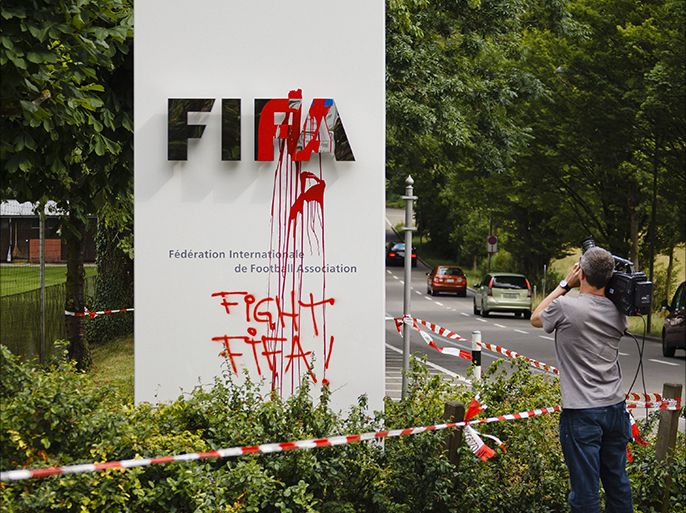 A television cameraman films the logo of FIFA after activists defaced it and sprayed "Fight Fifa", on a board near the headquarters of FIFA in Zurich on June 14, 2014. Hundreds of activists rallied on June 14, 2014 to express solidarity with Brazilian activists of the self-named group "Nao vai ter copa" (The World Cup will not happen). AFP PHOTO / MICHAEL BUHOLZER