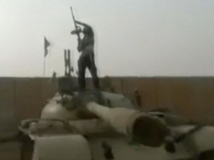 In this still image from video taken by militants on Wednesday, June 11, 2014, which has been authenticated based on its contents and other AP reporting, a militant standing on top of a tank holds a gun aloft at a military compound abandoned by the Iraqi military near Tikrit in Salah al-Din province, Iraq. The al-Qaida-inspired group that led this week's charge in capturing two key Sunni-dominated cities in Iraq vowed Thursday to march on to Baghdad, raising fears about the Shiite-led government's ability to slow the assault following lightning gains. (AP Photo/Militant video)