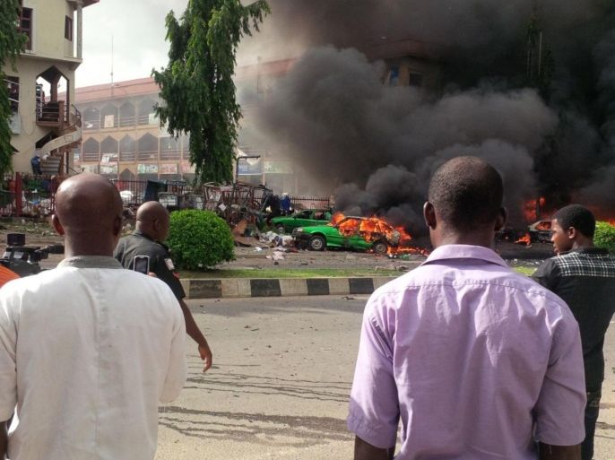 People watch as smoke fills the sky, after an explosion, at a shopping mall, Wednesday, June 25, 2014, in Abuja, Nigeria. An explosion rocked a shopping mall in Nigeria's capital, Abuja, on Wednesday and police say at least over 20 people have been killed and many wounded. Witnesses say body parts were scattered around the exit to Emab Plaza, in the upscale Wuse 11 suburb. (AP Photo)