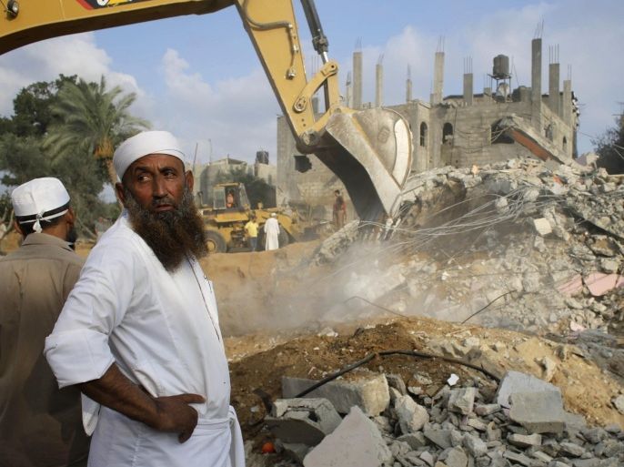 A Palestinian man looks on as a bulldozer searches for victims amongst the rubble of a house, which police said was destroyed in an Israeli air strike, in Khan Younis in the southern Gaza Strip July 21, 2014. Israeli tanks shelled militant targets in the Gaza Strip on Monday and a woman died in an air strike after the bloodiest day of a nearly two-week military offensive that showed no signs of abating, despite global calls for a truce. Palestinian health officials said the death toll since July 8 had reached 447, including many civilians, with a woman killed in the predawn strike in Beit Hanoun and 12 more bodies recovered from the embattled Shejaia neighbourhood where the number of fatalities rose to 72 from Sunday's fighting. Israel's army said it had been targeting militants from Gaza's dominant Hamas group, charging that they fired rockets from Shejaia and built tunnels and command centres there. The army said it had warned civilians to leave two days earlier. REUTERS/Ibraheem Abu Mustafa (GAZA - Tags: POLITICS CIVIL UNREST)