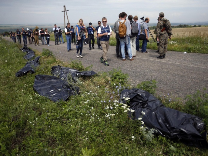 عمال الإنقاذ يضعون جثث ضحايا الطائرة الأوكرانية على حافة الطريق (رويترز)
