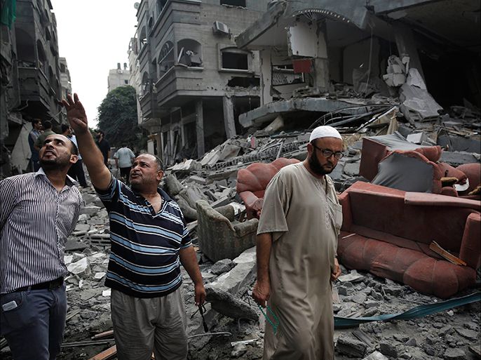 Palestinians gather in the rubble of a building that police said was hit by an overnight Israeli air strike, in Jabaliya in the northern Gaza Strip, July 24, 2014. Israel won a partial reprieve from the economic pain of its Gaza war on Thursday with the lifting of a U.S. ban on commercial flights to Tel Aviv, while continued fighting pushed the Palestinian death toll over 700. A truce remained elusive despite intensive mediation efforts. Israel says it needs more time to eradicate rocket stocks and cross-border tunnels in the Gaza Strip and Hamas Islamists demand the blockade on the enclave be lifted. REUTERS/Finbarr O'Reilly (GAZA - Tags: POLITICS MILITARY CIVIL UNREST CONFLICT)