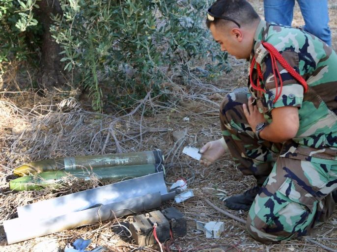 A Lebanese army expert dismantles two rockets that were found ready to fire into northern Israel, in the southern Lebanese village of Al-Mari, Lebanon, Friday, July. 11, 2014. The Lebanese army said in a statement that an "unknown side" fired three rockets Friday morning from the Marjayoun-Hasbaya region toward Israel. (AP Photo/Lotfallah Daher)