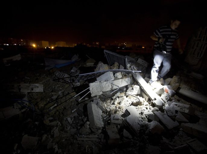 A Palestinian cameraman trudges over destruction following an Israel airstrike in Gaza City, on July 3, 2014. Israeli warplanes launched in the early morning, dozens of airstrikes on different targets in the Gaza Strip, including sites belonging to Hamas. AFP PHOTO/MOHAMMED ABED
