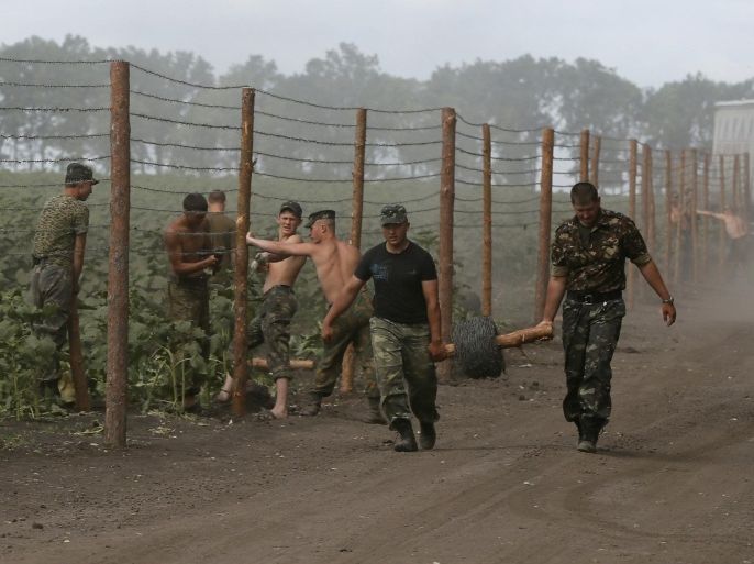 Ukrainian soldiers set up a barbed wire fence at a temporary base near the city of Slaviansk July 6, 2014. Ukrainian forces routed pro-Russian rebels in a flashpoint area of eastern Ukraine on Saturday and raised the country's blue and yellow flag again over what had for months been the separatist redoubt of Slaviansk. REUTERS/Gleb Garanich (UKRAINE - Tags: POLITICS CIVIL UNREST MILITARY)