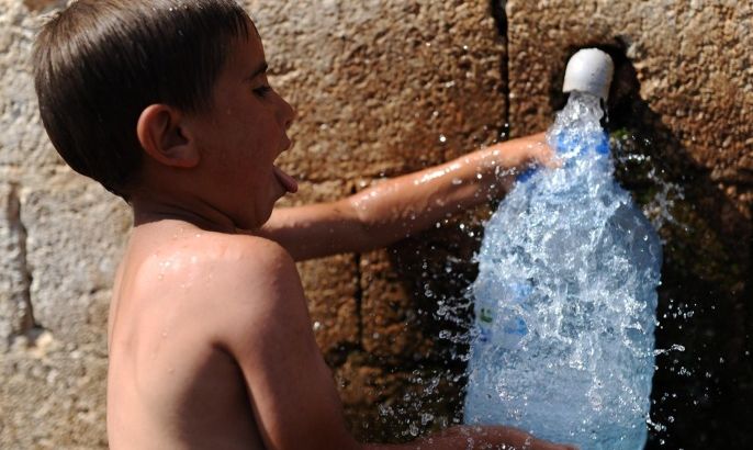 A boy fills a bottel with water in his village near the Turkish city of Reyhanli, on September 1, 2013.