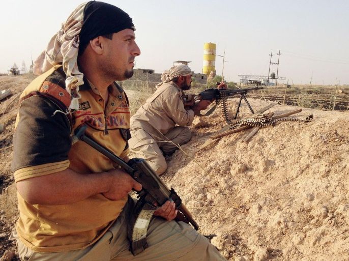 In this Friday, July 4, 2014 photo, fighters with the "Peace Brigades" hold their weapons in their combat positions on the outskirts of Samarra, 60 miles (95 kilometers) north of Baghdad, Iraq. Fighters of the voluntary armed group formed after the radical Shiite cleric Muqtatda al-Sadr called to protect holy shrines against possible attacks by Sunni militants have been deployed to protect the Shiite holy al-Askari shrine in the city of Samarra. Islamic extremists have destroyed at least 10 ancient shrines and Shiite mosques in territory - the city of Mosul and the town of Tal Afar - they have seized in northern Iraq in recent weeks. (AP Photo/Loay Hameed)