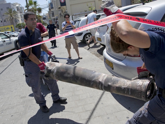 ‪‬ خبراء متفجرات يحملون قذيفة فلسطينية سقطت على أحد المواقع الإسرائيلية(أسوشيتد برس)