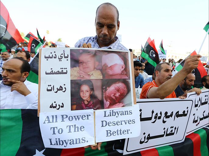 Libyans hold placards, one showing pictures of injured children, during a protest against the new anti-Islamist parliament on August 15, 2014 in Martyrs' Square in the Libyan capital Tripoli. A majority of Libyan MPs voted on August 13, 2014 to call for foreign intervention to protect civilians amid chaos in the North African country as rival militias engage in fierce clashes, a deputy said. The parliament, elected on June 25, met in Tobruk between Benghazi and the border with Egypt, because of the violence plaguing both of Libya’s main cities.    AFP PHOTO / MAHMUD TURKIA