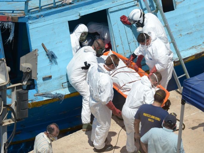 Rescuers carry the body of a migrant at the Valletta port in Malta on July 20, 2014 a day after a rescue operation at sea. Italian and Maltese rescuers found 18 bodies on an overcrowded migrant boat yesterday, with Italian officials blaming toxic fumes from the engine and the Maltese military saying there could have been a stampede.Three asylum-seekers were evacuated by Italian coastguards and rushed to hospital. One of them died on the way and two others were in a serious condition, officials said. The boat is estimated to have had 400 people on board and was first spotted by a Danish ship south of the Italian island of Lampedusa in waters between Libya and Malta. AFP PHOTO / MATTHEW MIRABELLI