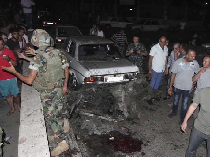 Lebanese soldiers and residents inspect a car wreck in Tripoli August 6, 2014. A bomb exploded in the Lebanese city of Tripoli on Wednesday, killing one person and wounding seven others, security sources said. It was not immediately clear what had been targeted.Ambulances were seen rushing to the area of the blast, which was cordoned off by the military.Tensions have flared in Tripoli, a predominantly Sunni Muslim city, in recent days as a result of clashes between the army and Islamist militants in the border town of Arsal, which is also predominantly Sunni. Earlier, unidentified gunmen opened fire on soldiers in Tripoli when they removed a roadblock being set up in protest at the army's operations in Arsal. Picture taken August 6, 2014. REUTERS/Omar Ibrahim (LEBANON - Tags: POLITICS CIVIL UNREST)