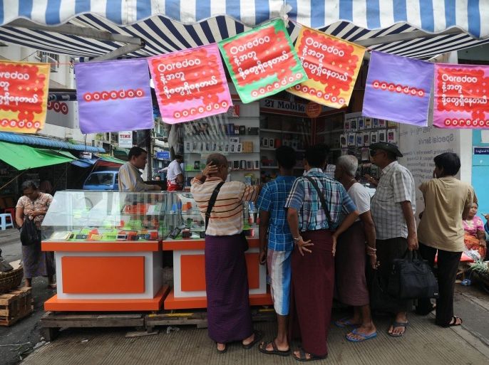This photo taken on August 1, 2014 shows people buying Ooredoo mobile phone SIM cards from a shop in Yangon. Qatari telecoms firm Ooredoo began selling low-cost SIM cards in Myanmar on August 2, opening up access to mobile services in one of the world's last virtually untapped phone markets. AFP PHOTO/SOE THAN WIN