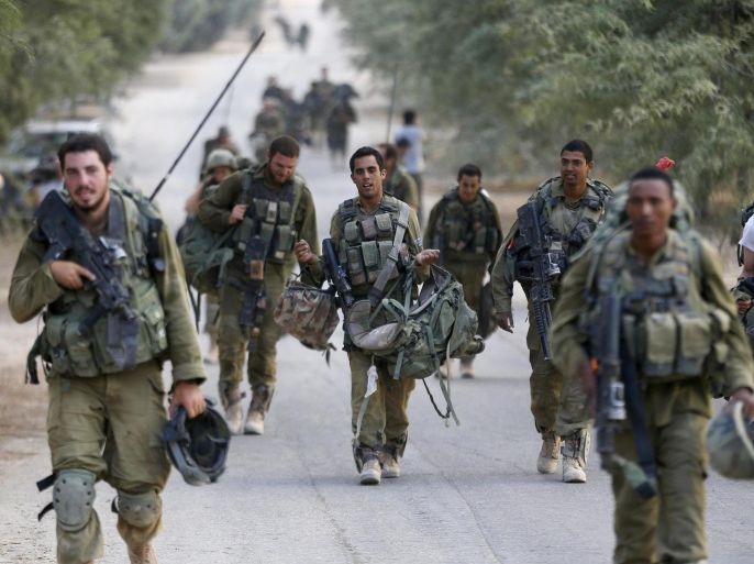 An Israeli soldier from the Nahal Brigade carry equipment after returning to Israel from Gaza August 5, 2014. Israel pulled its ground forces out of the Gaza Strip on Tuesday and started a 72-hour ceasefire with Hamas mediated by Egypt as a first step towards negotiations on a more enduring end to the month-old war. REUTERS/Baz Ratner (ISRAEL - Tags: POLITICS CONFLICT CIVIL UNREST MILITARY)