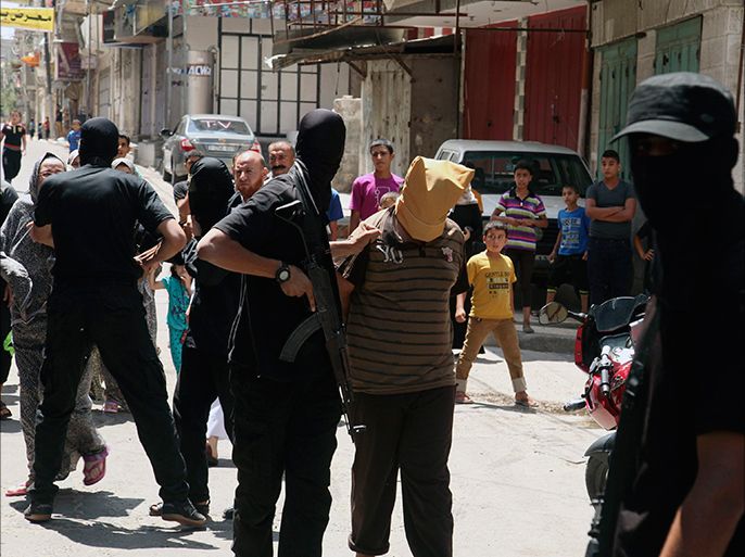A Hamas militant grabs a Palestinian suspected of collaborating with Israel, before executing him in Gaza City August 22, 2014. Hamas militants killed seven Palestinians suspected of collaborating with Israel in a public execution in a central Gaza square on Friday, witnesses and a Hamas website said. The victims, their heads covered and hands tied, were shot dead by masked gunmen dressed in black in front of a crowd of worshippers outside a mosque after prayers, witnesses and al-Majd, a pro-Hamas website, said. Another 11 people suspected of collaborating with Israel were killed by gunmen at an abandoned police station in Gaza earlier on Friday, Hamas security officials said. REUTERS/Stringer (GAZA - Tags: POLITICS CIVIL UNREST MILITARY CONFLICT TPX IMAGES OF THE DAY)