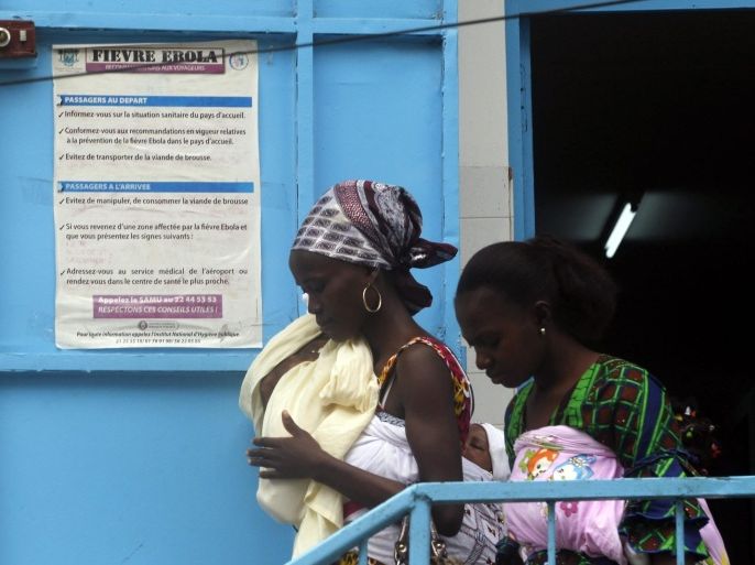 Women walk near a poster displaying a government message against Ebola, at a maternity hospital in Abidjan August 14, 2014. The world's worst outbreak of Ebola has claimed the lives of 1,069 people and there are 1,975 probable and suspected cases, the vast majority in Guinea, Liberia and Sierra Leone, according to new figures from the World Health Organisation (WHO). Ivory Coast has recorded no cases of Ebola. REUTERS/Luc Gnago (IVORY COAST - Tags: HEALTH)