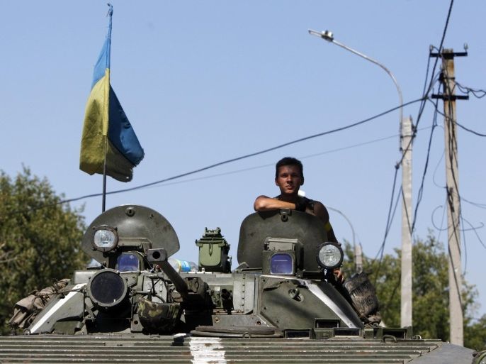 A Ukrainian serviceman sits atop an armoured vehicle as he guards a checkpoint outside Donetsk, August 15, 2014. The European Union said on Friday it would consider any unilateral military actions by Russia in Ukraine as "a blatant violation of international law". REUTERS/Valentyn Ogirenko (UKRAINE - Tags: MILITARY POLITICS CIVIL UNREST CONFLICT)