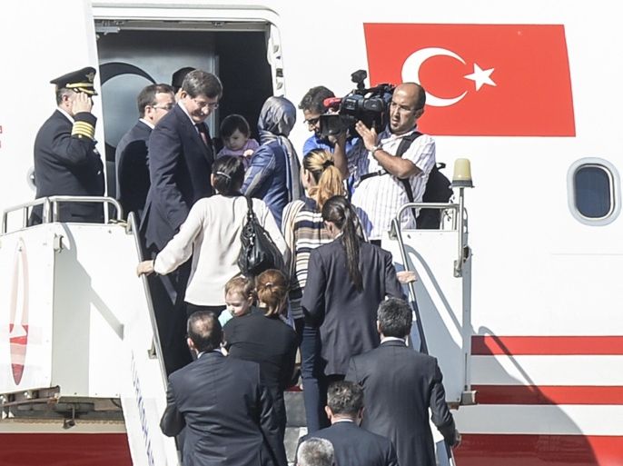 Turkish Prime Minister Ahmet Davutoglu (L) gets into his plane with hostages on September 20, 2014, at the airport of the southern Turkish city of Sanliurfa near the Syrian border. These people were part of dozens of Turkish nationals held hostage by Islamic State jihadists in northern Iraq for more than three months who have been released and brought to Turkey. IS jihadists kidnapped 49 Turks including diplomats, children and special forces from the Turkish consulate in Mosul on June 11 as they captured swathes of northern Iraq. AFP PHOTO/BULENT KILIC