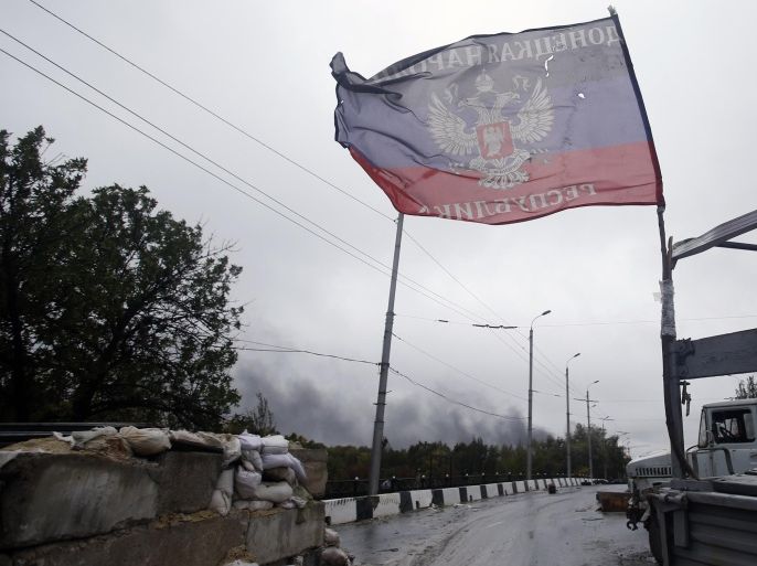 Smoke rises after shelling over a checkpoint marked with flag of the self-proclaimed Donetsk People's Republic in the town of Donetsk, eastern Ukraine, Wednesday, Sept. 24, 2014. Mortar fire struck an apartment block in the rebel-held city of Donetsk overnight, yet another violation of a cease-fire declared weeks earlier between government forces and pro-Russian insurgents. The attack came even as both sides claimed to be pulling back heavy artillery to set up a buffer zone. (AP Photo/Darko Vojinovic)