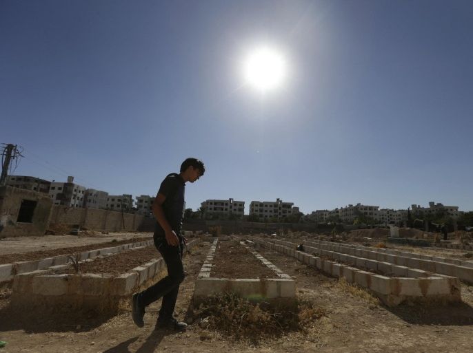 A man walks beside mass graves of people who died during chemical attacks on Zamalka, in Eastern Ghouta, a suburb of Damascus August 21, 2014. A year passed since the chemical attacks on Eastern Ghouta of Damascus. REUTERS/Bassam Khabieh (SYRIA - Tags: POLITICS CIVIL UNREST CONFLICT)