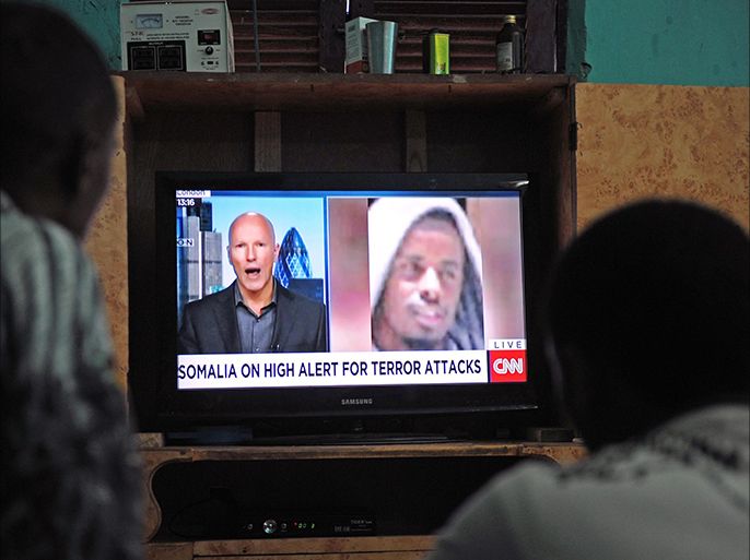 Somali men watch the news on September 6, 2014 in Mogadishu on a television set where is broadcasted a portrait of Somalia's Al-Qaeda-linked Shebab slain leader Ahmed Abdi Godane, recently killed in a US air strike