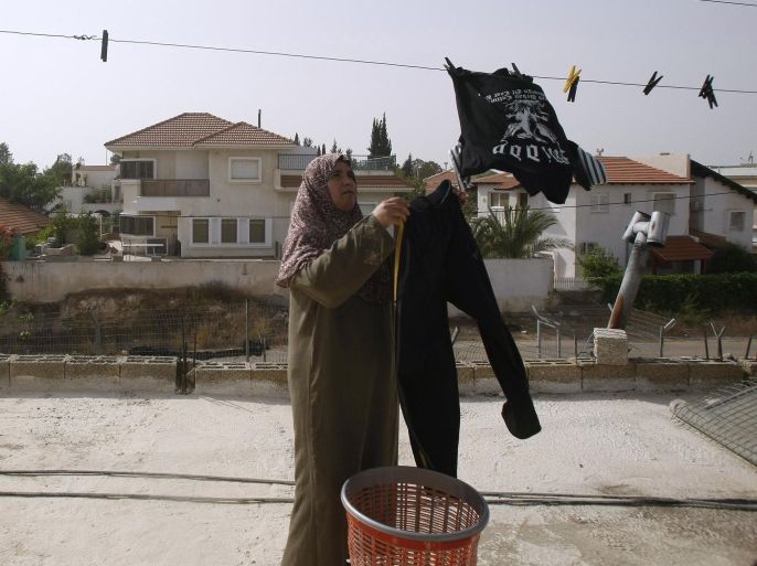 A Palestinian woman hangs clothes at her courtyard which faces the Jewish settlement of Elkana in the northern West Bank, on September 26, 2010. Jewish settlers were to start building as a settlement freeze expired, despite efforts by Mideast leaders to defuse a major crisis facing peace talks.