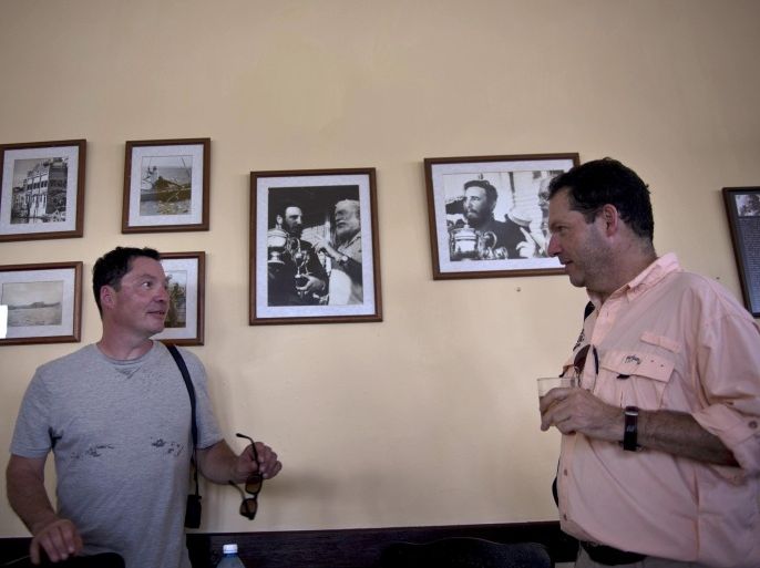 John Hemingway, right, speaks with his brother Patrick next to photos of their grandfather Ernest Hemingway with Fidel Castro as they arrive to eat at La Terraza restaurant in Cojimar, Cuba, Monday, Sept. 8, 2014. Along with a team of U.S. researchers, the Hemingway brothers are on a five-day mission to leverage their famous name to encourage closer ties between the United States and Cuba and, hopefully, open the way for scientists to gain access to the writer's fishing logs, a long-concealed and potentially valuable source of knowledge about the area's massive predatory game fish. (AP Photo/Ramon Espinosa)