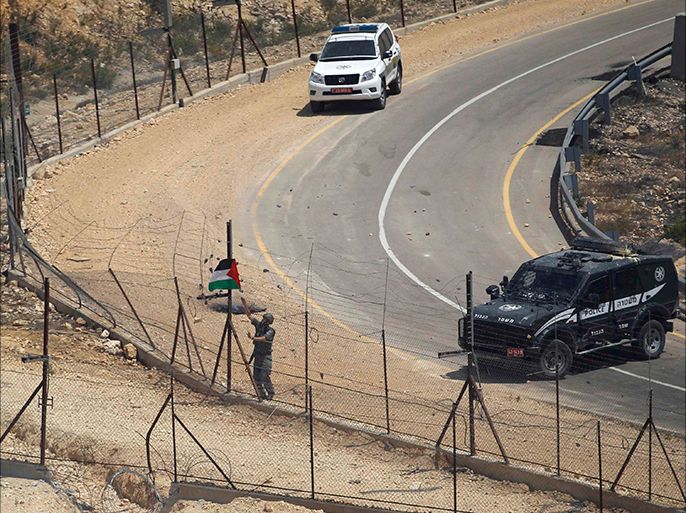An Israeli border police removes a Palestinian flag at the Israeli barrier fence during clashes with Palestinian protesters following the funeral of Palestinian Oday Jaber, whom medics said was killed by Israeli troops during Friday clashes at a protest against the Israeli offensive in Gaza, in the West Bank village of Rafat near Ramallah August 2, 2014. Israeli forces killed two Palestinians in clashes in the occupied West Bank on Friday, Palestinian medical officials said. The violence erupted when a few thousand Palestinians took to the street to protest Israel's military operation in the Gaza Strip. Both men were killed by live fire in two separate incidents, Palestinian medical officials said. An Israeli military spokeswoman said troops shot one man in the city of Tulkarm after violence got out of control, with protesters throwing stones and gasoline bombs at soldiers. In the second incident near the city of Ramallah, the spokeswoman said troops resorted to using live fire after protesters were not deterred by riot-dispersal means that troops had deployed initially. REUTERS/Mohamad Torokman (WEST BANK - Tags: POLITICS CIVIL UNREST)