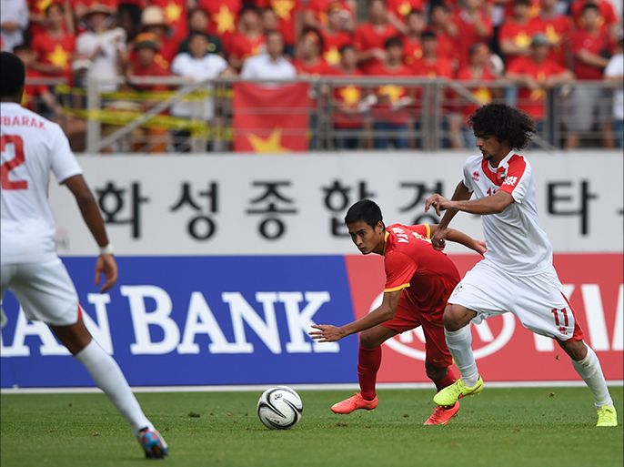 Vu Minh Tuan (C) of Vietnam clashes with Hassan Abdullah Waled Hussain (R) of the United Arab Emirates (UAE) during their men's round of 16 football match of the 2014 Incheon Asian Games, at Hwaesong Sports Complex some 50km from Incheon on September 26, 2014. UAE won 2-1. AFP PHOTO / Ed Jones