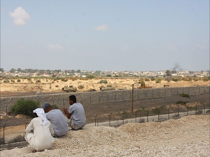 فلسطينون على الجانب الفلسطيني من الحدود مع مصر يرقبون تحركات آليات للجيش المصري أثناء تقدمها للقيام بعمليات تجريف على الحدود، الصورة التقطت في الثالث من سبتمبر من العام الماضي 2013.
