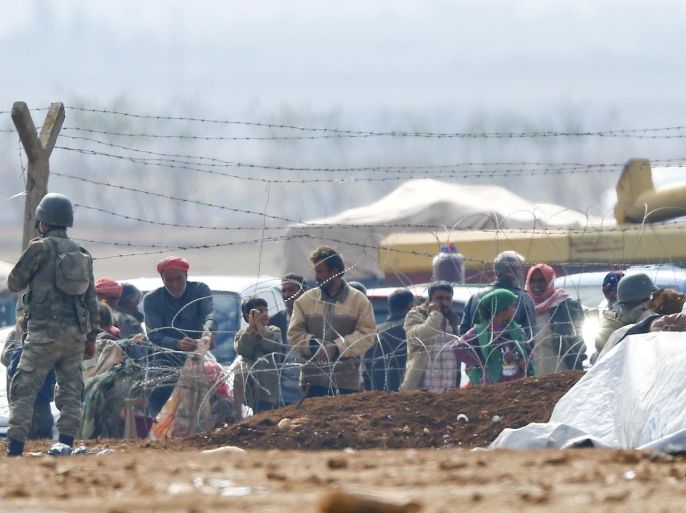 A Turkish soldier stands guard as Syrian Kurdish refugees wait behind the border fences to cross into Turkey near the southeastern town of Suruc in Sanliurfa province , October 17, 2014. A U.S. State Department official held direct talks for the first time last weekend with a Syrian Kurdish group involved in the fight against Islamic State in Syria, including the besieged town of Kobani, the State Department said on Thursday. REUTERS/Kai Pfaffenbach (TURKEY - Tags: MILITARY CONFLICT POLITICS)