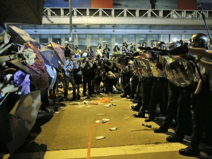 Riot police officers try to stop protesters from moving forward on a pro-democracy protest encampment in the Mong Kok district of Hong Kong early Sunday, Oct. 19, 2014. Hong Kong riot police battled with thousands of pro-democracy protesters for control of the city's streets Saturday, using pepper spray and batons to hold back defiant activists who returned to a protest zone that officers had partially cleared. (AP Photo/Vincent Yu)