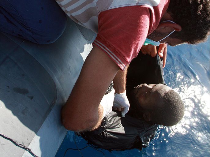 Libyan coast guards rescue an illegal migrant from sub-Saharan Africa after his boat sank off the coastal town of Guarabouli, 60 km (36 miles) east of the capital Tripoli on October 2, 2014. Between 80 and 90 people were rescued, a coast guard officer said, adding that survivors said there had been up to 180 people on board. AFP PHOTO / MAHMUD TURKIA