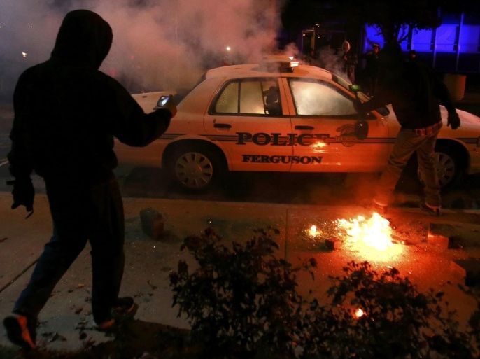 A protester videos a police car set on fire by protesters in Ferguson, Missouri, November 25, 2014. Missouri's governor ordered hundreds more National Guard troops to the St. Louis suburb rocked by rioting after a white policeman was cleared in the fatal shooting of an unarmed black teenager REUTERS/Adrees Latif (UNITED STATES - Tags: CRIME LAW CIVIL UNREST)