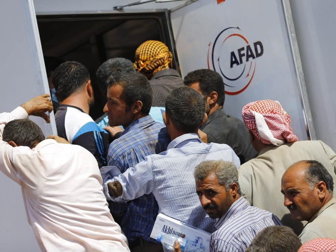 لاجئون أكراد سوريون ينتظرون في صف لتسجيل أنفسهم بعد عبورهم للأراضي التركية (رويترز)