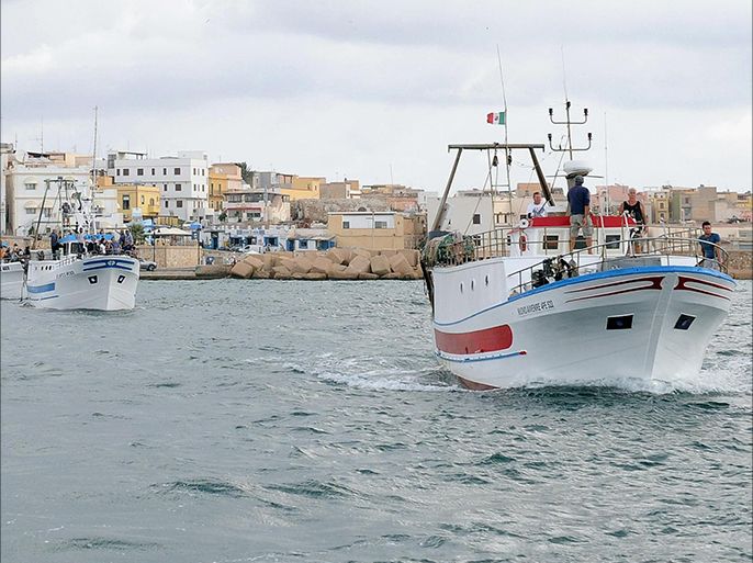 epa03897224 Boats leave Lampedusa harbor, Italy, on 05 October 2013 bringing local fishermen to the site off the coast where a vessel carrying migrants sank on 03 October. They were throwing a wreath to the waters off the Lampedusa island to pay a last respect to those who lost their lives in the most serious migrant boat accident in recent years. The provisional death toll on 04 October stood at 111 with 155 survivors and an unspecified number of people missing. EPA/ETTORE FERRARI