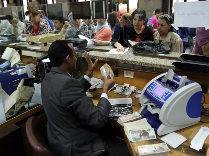 A bank teller receives money from people willing to buy investment certificates for the Suez Canal project at the National Bank of Egypt, in Cairo, Egypt, 08 September 2014. According to media reports, four state-owned banks began on 04 September issuing investment certificates to finance the projects of upgrading the Suez Canal. The new certificates, with values ranging 10 to 1000 Egyptian pounds each (about one to 105 euros), are issued with five years maturity at 12 % annual interest rate. Egyptian authorities on 05 August announced plans for a major upgrade of the 145 years old Suez Canal. The project will involve digging 35 km of a new parallel canal and widening the existing canal along further 37 km.