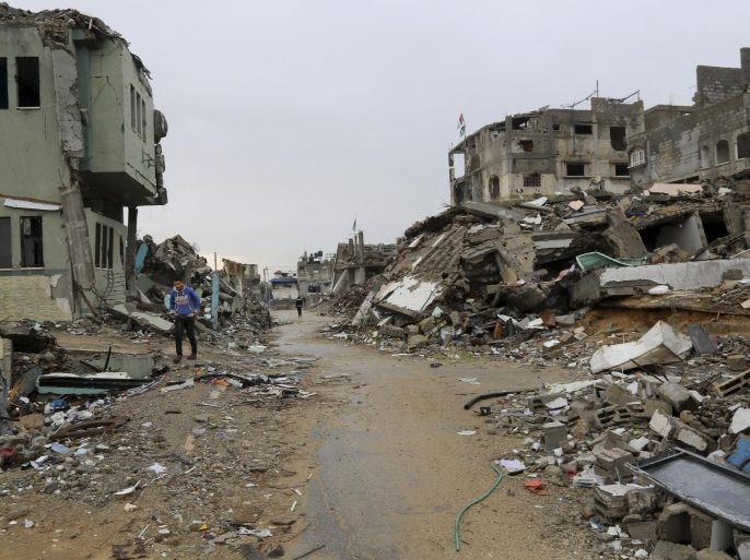 Palestinians walk past destroyed homes from recent conflict between Israel and Hamas in Shijaiyah, neighborhood in Gaza City, Monday, Nov. 24, 2014. (AP Photo/Adel Hana)