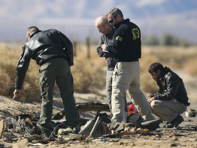 Investigators from the National Transportation Safety Board (NTSB) look at wreckage from the crash of Virgin Galactic's SpaceShipTwo near Cantil, California November 2, 2014. A suborbital passenger spaceship being developed by Richard Branson's Virgin Galactic company crashed during a test flight on Friday at the Mojave Air and Space Port in California, killing one crew member and seriously injuring the other, officials said. REUTERS/David McNew (UNITED STATES - Tags: TRANSPORT DISASTER SCIENCE TECHNOLOGY BUSINESS)